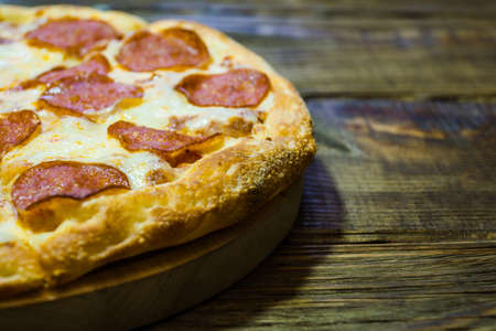 Italian Pepperoni pizza with salami on dark wooden background. Italian traditional food. A textured background. Copy paste placeの写真素材