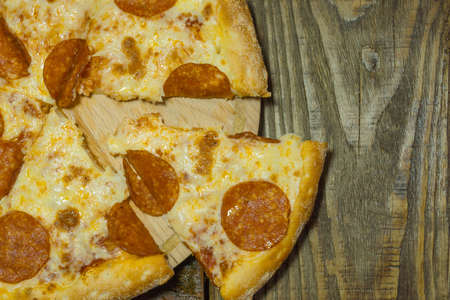Italian Pepperoni pizza with salami on dark wooden background. Italian traditional food. A textured background. Copy paste placeの写真素材