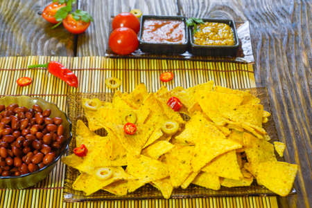 Nachos with Tortilla chips tomato salsa, bean and mustard on rustic wooden background.A textured background.Copy paste placeの写真素材