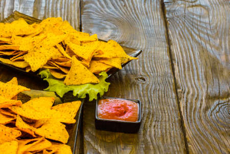Nachos with Tortilla chips tomato salsa and mustard on rustic wooden background. A texture...