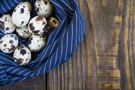 quail eggs on a napkin in the shape of a nest on a rustic wooden background