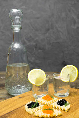 Caviar on toast and two glasses of vodka on a wooden table.の写真素材
