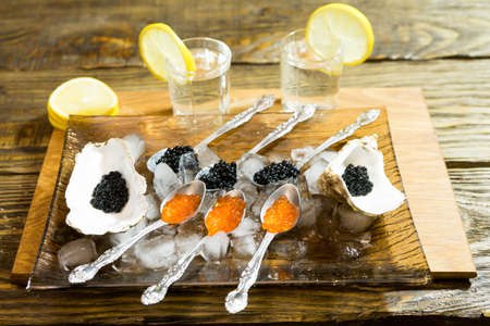 black caviar to oysters, and spoon on the ice, next to two cups of vodka.の写真素材