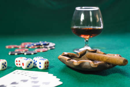 Cards, dice, chips, a glass of cognac and cigar on a green baize, the game is