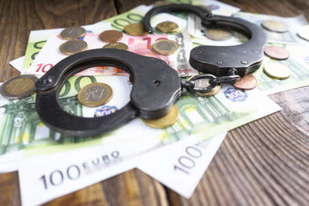 Handcuffs on a pile of euro banknotes. The symbolic meaning of economic crimes. Copy paste.の写真素材