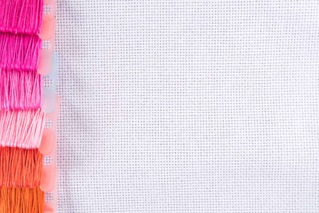 Colored thread for embroidery on white canvas.