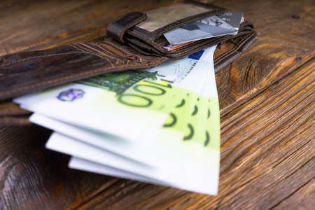 Leather wallet with hundreds and credit cards lying on a wooden table. Copy pasteの写真素材