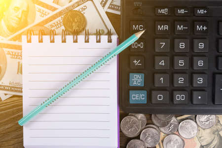 Calculator, banknotes, coins notepad and pen on the wood table. Copy pasteの写真素材