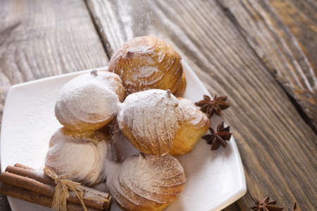 Delicious eclairs sprinkled with icing sugar, stand on a wooden table.の写真素材