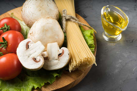 Mushrooms mushrooms, lettuce, tomatoes and spaghetti on stone table.の写真素材