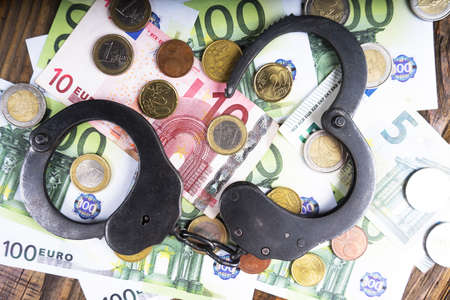 Handcuffs on a pile of euro banknotes. The symbolic meaning of economic crimes. Copy pasteの写真素材