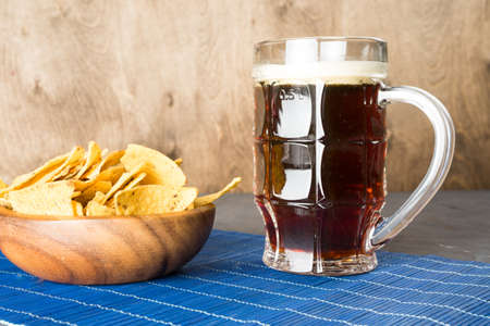 Dark beer, nachos and fish chips are on the table.の写真素材