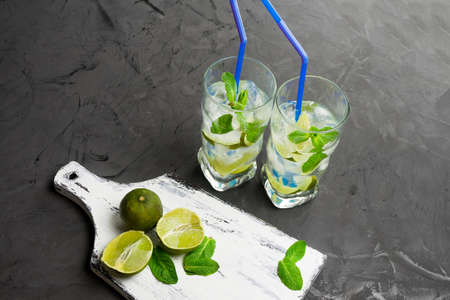 Mojito in glasses, next to lime and mint on the cutting Board. Copy space.の写真素材