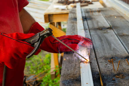 Welder welds two pieces. Hands protected red leather gloves. Copy cpase.