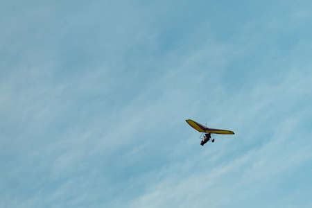 The hang-glider on a background blue sky with light clouds. Flying a gyroplane. Copy space.