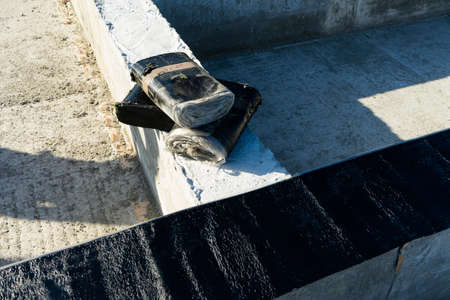 Workers carry out waterproofing of the Foundation for the construction of a wooden house.の写真素材