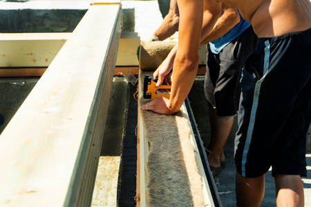 Construction of a wooden house made of profiled laminated veneer lumber. Laying insulation under the timber.の写真素材