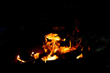 Flames of fire from burning coals in the grill late at night.