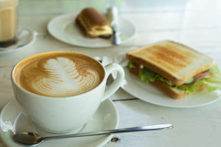 A cup of cappuccino and sandwich ham cheese on the plateの写真素材