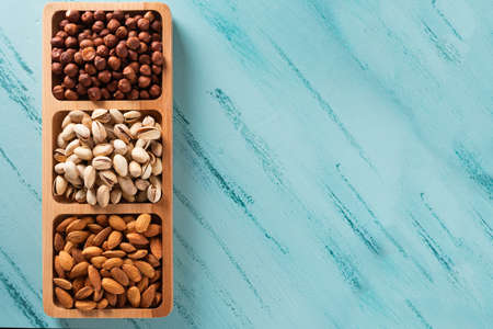 Compartmental dish with nuts on blue wooden table.の写真素材