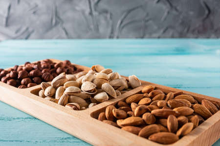 Compartmental dish with nuts on blue wooden table.の写真素材