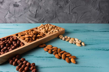 Compartmental dish with nuts on blue wooden table.の写真素材