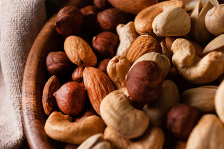 Assortment of nuts in wooden bowl on dark wooden table.の写真素材
