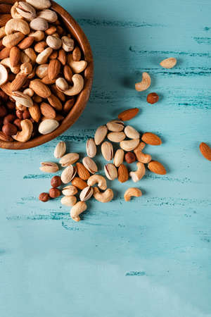 Assortment of nuts in wooden bowl on blue wooden table.の写真素材