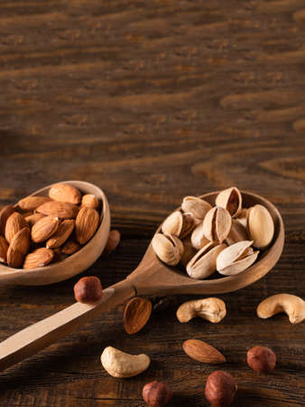Nuts in wooden spoons on a dark wooden tableの写真素材