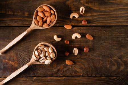 Nuts in wooden spoons on a dark wooden tableの写真素材