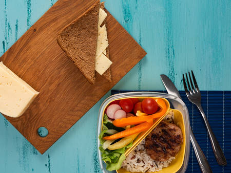 Lunch box with appetizing food and on light wooden tableの写真素材