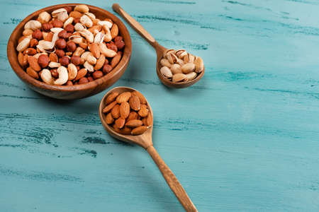 Assortment of nuts in wooden bowl on blue wooden table. Cashew, hazelnuts, almondsの写真素材