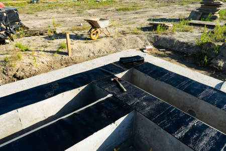 Workers carry out waterproofing of the Foundation for the construction of a wooden house. Copy paste.の写真素材