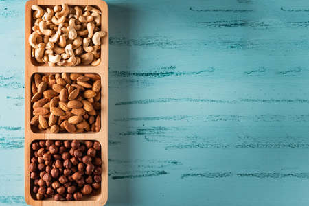 Compartmental dish with nuts on blue wooden table.の写真素材