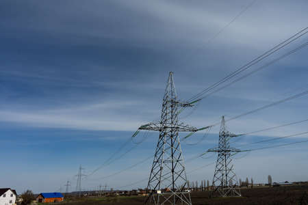 High voltage lines and power pylons on a sunny day with cirrus clouds in the blue sky.の写真素材