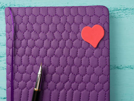A Notepad and pen lie on a vintage wooden background. Red hearts around. Mock up Valentine dayの写真素材