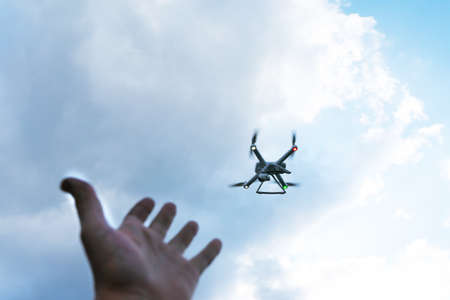 The man's hand reaches for the flying drone. Drone in focus