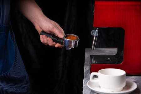A man with a portafilter in his hands. The concept of making coffee in a coffee machine. Photo in a low keyの写真素材