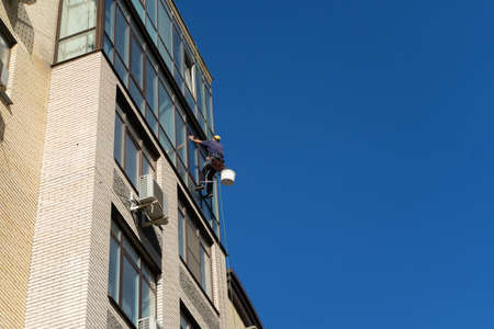 Industrial climbing. Climber wash windows in a high-rise building. Cleaning of windows glass elementsの写真素材