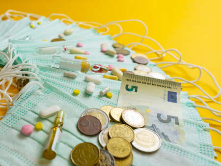 The concept of inflation in medicine. Medical masks, medicines and money on a yellow background