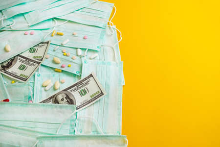 Sale of medical masks. Protective medical mask and different types of pills next to money on yellow...