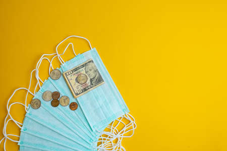 The concept of inflation in medicine. Medical masks, medicines and money on a yellow background.の写真素材