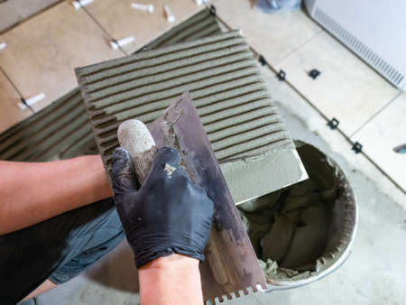 Applying thinset mortar on a tile. Apply the adhesive, closeup.の写真素材