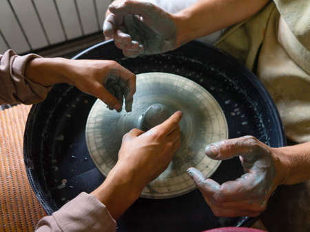 The master of the pottery craft teaches the student to work on the potters wheel. Creating dishes from clay. Selective focus.の写真素材
