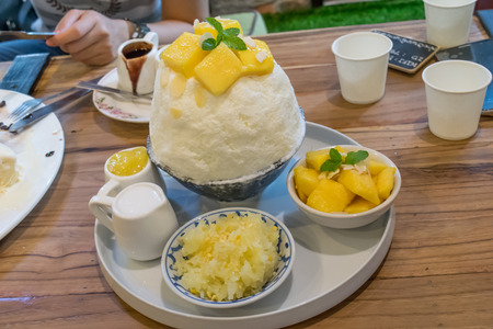 Bingsu ( Korean desserts ) mango served with sweetened condensed milk and sticky rice on tableの写真素材