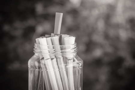 Abstract black and white image various color pen in glass bottle on concrete floor with green bush background. (Selective focus)の写真素材