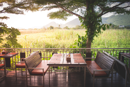 Wooden dining table and chair in restaurant with beautiful natural view and sunlight background. (Selective focus)の写真素材