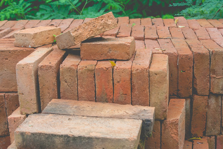 Side view close up stack of brown bricks with green natural background at construction site. (Selective focus)の写真素材