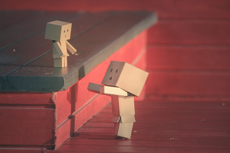 Adorable Family Concept : Little paper dolls standing on wooden stairs with sunlight in the morning.の写真素材