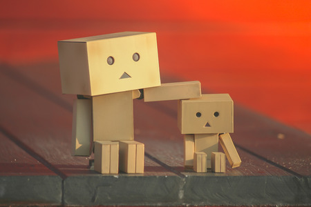 Adorable Family Concept : Little paper dolls sitting on wooden stairs with sunlight in the morning....